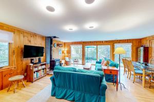 a living room with a blue couch and a television at Dog-friendly 3-story home with wood stove, deck, grill, ocean views, W/D, AC in Southwest Harbor