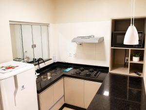 a kitchen with a stove and a white refrigerator at Vêneto Flat Residence (AP-02) in Primavera do Leste +5 photos