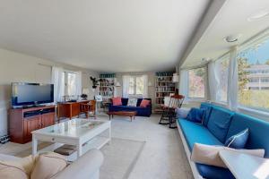 a living room with a blue couch and a tv at Ocean Point Colony Home w/ Sunroom & Sweeping Ocean Views, Dog-friendly in East Boothbay