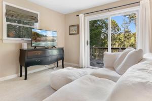 a living room with a tv and a couch and a desk at Tranquil private riverfront home w/ tidal dock & large yard in Boothbay +34 photos