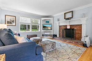 a living room with a blue couch and a fireplace at Tranquil private riverfront home w/ tidal dock & large yard in Boothbay
