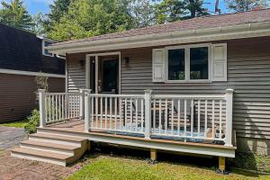 a house with a wooden porch with a white railing at Secluded waterfront home with private dock, outdoor dining, firepit, WiFi & W/D in Orland