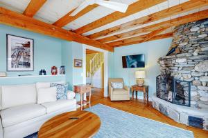 a living room with a white couch and a stone fireplace at Enchanting Oceanfront Cottage with Breathtaking Views and Modern Comforts in East Boothbay +17 photos