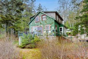 a green house in the middle of a forest at Bayfront cottage with fantastic views & minutes to downtown - Dog-friendly in Boothbay Harbor