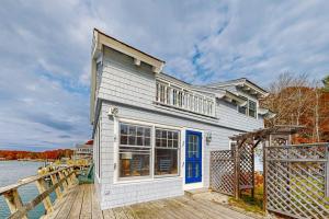 a white house on a dock next to the water at Enchanting Oceanfront Cottage with Breathtaking Views and Modern Comforts in East Boothbay