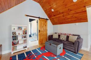 a living room with a couch and a book shelf at Luxurious waterfront home with deck, firepit, hot tub, fireplace, & pool table in Boothbay