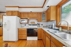 a kitchen with wooden cabinets and a white refrigerator at Secluded waterfront home with private dock, outdoor dining, firepit, WiFi & W/D in Orland +27 photos