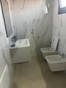 a white bathroom with a sink and a toilet at Apartament E&G in Rrogozhinë