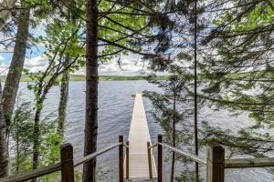 a wooden bridge over a body of water with trees at Lakefront Chalet-Style Home with Large Deck, a Dock & Beautiful Lake Views in Greenville