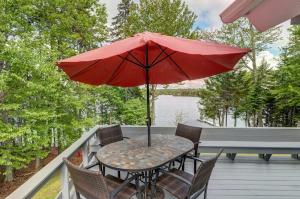 a table and chairs with a red umbrella on a deck at Lakefront Chalet-Style Home with Large Deck, a Dock & Beautiful Lake Views in Greenville