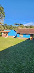 a blue building with a large field of grass at Aconchego Mineiro in Visconde De Maua