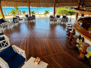 a restaurant with a bar and tables and chairs at Tiki Beach Club & Resort in Paje