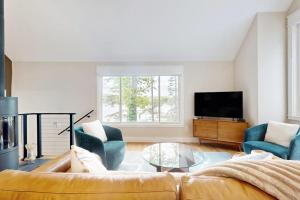 ein Wohnzimmer mit Sofa, zwei Sesseln und einem Fernseher in der Unterkunft Stunning riverfront home, hot tub, BBQ, and washer & dryer in Edgecomb