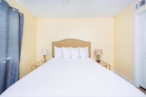 a bedroom with a large white bed with two lamps at Lei Lani 108 condo in Orange Beach