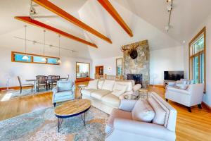 a living room with white furniture and a stone fireplace at Delightful oceanfront home with amazing views, wrap-around deck & two fireplaces in Wiscasset