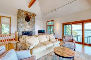a living room with a couch and a stone fireplace at Delightful oceanfront home with amazing views, wrap-around deck & two fireplaces in Wiscasset
