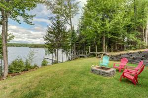 three chairs sitting on a lawn next to a lake at Lakefront Chalet-Style Home with Large Deck, a Dock & Beautiful Lake Views in Greenville