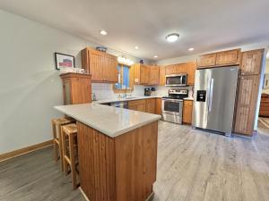a kitchen with wooden cabinets and a stainless steel refrigerator at Riverfront home w/ deck, amazing views & firepit - near the best of Maine in Stockton Springs +24 photos