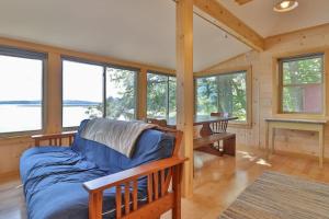 a living room with a blue couch in a room with windows at Luxe Bayfront Cabin w/ Stunning Views & Shared Dock- Ideal for Hunting & Fishing in Bowdoinham