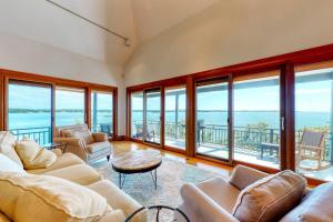 a living room with couches and a view of the ocean at Delightful oceanfront home with amazing views, wrap-around deck & two fireplaces in Wiscasset