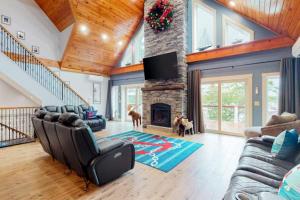 a living room filled with furniture and a stone fireplace at Luxurious waterfront home with deck, firepit, hot tub, fireplace, & pool table in Boothbay