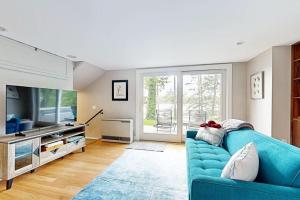 ein Wohnzimmer mit einer blauen Couch und einem Fernseher in der Unterkunft Stunning riverfront home, hot tub, BBQ, and washer & dryer in Edgecomb