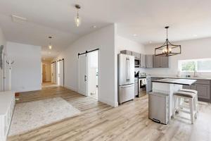 a kitchen with white walls and wooden floors and a refrigerator at Elegant Oceanfront Condo with Stunning Harbor Views & Spectacular Sunsets in Boothbay Harbor