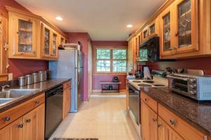 a kitchen with wooden cabinets and stainless steel appliances at Gorgeous lakefront home w/ dock, canoe, kayaks & lake/forest views in Ellsworth +29 photos