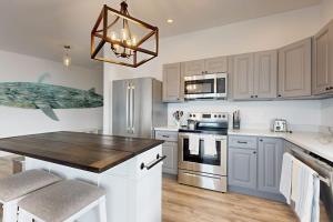 a kitchen with white cabinets and a wooden counter top at Elegant Oceanfront Condo with Stunning Harbor Views & Spectacular Sunsets in Boothbay Harbor