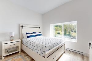 a white bedroom with a bed and a window at Elegant Oceanfront Condo with Stunning Harbor Views & Spectacular Sunsets in Boothbay Harbor +11 photos