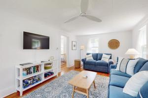 a living room with a blue couch and a tv at Tranquil Seaside Cottage with Spectacular Views, Wifi & Washer/Dryer in Boothbay