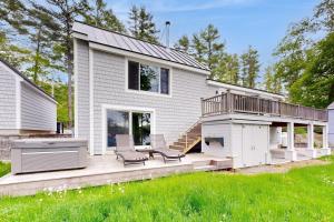 ein Haus mit einer Terrasse, auf der zwei Stühle stehen in der Unterkunft Stunning riverfront home, hot tub, BBQ, and washer & dryer in Edgecomb