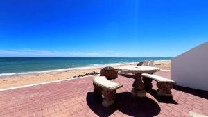 a picnic table and benches on the beach at Comfortable Beachfront Condo Las Olas II 1 in Puerto Peñasco