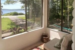 a room with three windows with a view of a yard at Ocean-view cottage near beach with deck, grill, & full kitchen in Bristol