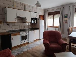 a kitchen with white cabinets and a red chair and a table at Casa Montse - Derecha in Colombres +9 photos