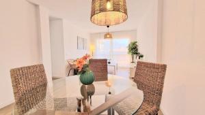 a dining room with a glass table with chairs and a vase with flowers at Apartamento Fuengirola Costa in Fuengirola