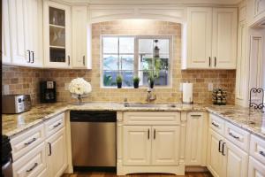 a kitchen with white cabinets and a sink and a window at Lavish 5 Bedroom, 4 Bath Pool Home 3/4 Mile To Disney in Anaheim