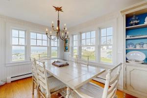 a dining room with a white table and a chandelier at Oceanfront home incredible ocean views, deck & location in Boothbay