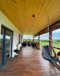 a porch with a hammock hanging from a wooden ceiling at Wakacyjne relaksacyjnie in Szczytno