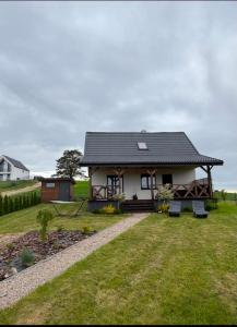 a small white house with a gambrel roof at Wakacyjne relaksacyjnie in Szczytno