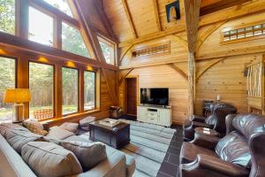 a large living room with leather furniture in a log cabin at The Cabin on 32 wooded acres - tranquil new-build with sauna & forested views in Franklin