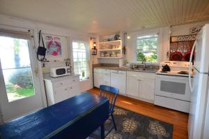 a kitchen with white cabinets and a blue bench in it at Berry Cottage, private dock, overlooking a sandy b in South Thomaston