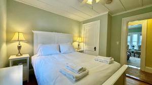 a bedroom with a large white bed with towels on it at Commanders Cabin, quaint apt steps to downtown in Camden