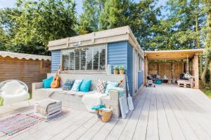 a blue tiny house with a couch on a deck at Ibiza Summer Lodge in Brouwershaven