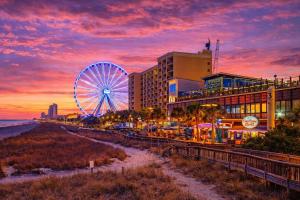 a ferris wheel in front of a building and a beach at Updated Oceanfront Suite by Skywheel Yachtsman 902 in Myrtle Beach