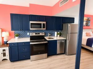 a small kitchen with blue cabinets and a bed at Updated Oceanfront Suite by Skywheel Yachtsman 902 in Myrtle Beach
