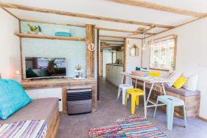 a living room with a bed and a table and a kitchen at Ibiza Summer Lodge in Brouwershaven