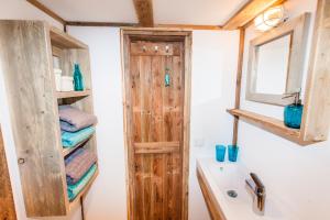 a bathroom with a wooden door next to a sink at Ibiza Summer Lodge in Brouwershaven +34 photos