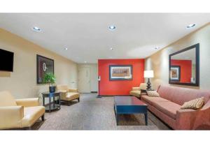a lobby with couches and chairs and a red wall at Motel 6 Fairfield OH Cincinnati in Fairfield