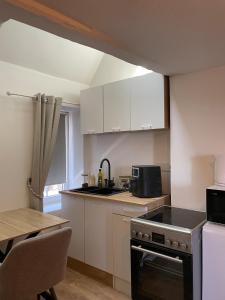 a kitchen with white cabinets and a stove top oven at Duplex de caractère in Coutances